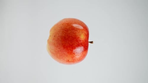 Vertical Video Closeup of Ripe Delicious Apple Spinning in Slow Motion at White Background Closeup