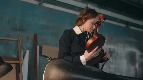 Young Woman Carefully Holds a Violin