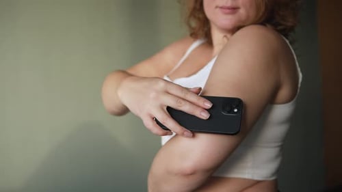 Mujer joven controla el nivel de azúcar en sangre con un sensor y un teléfono inteligente