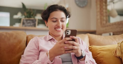 Woman Using Mobile Phone and Smiling on Couch