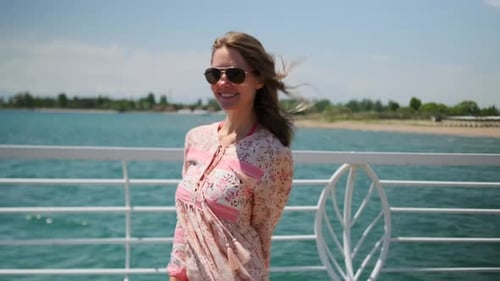 A woman on seascape waves hand dancing on beach pier against background of blue sky in flowing dress