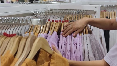 A Woman in a Clothing Store Chooses Her Size From a New Collection On the Hangers of the Boutique