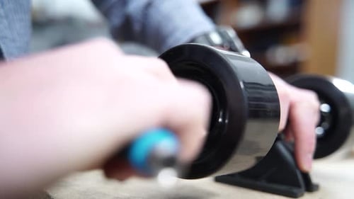 Young caucasian man attached a wheel to his electric skateboard with an Allan key.