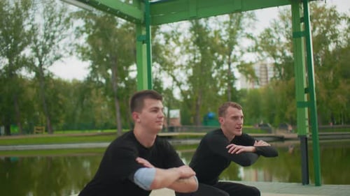 Men Training Together Doing Squats in Urban Park