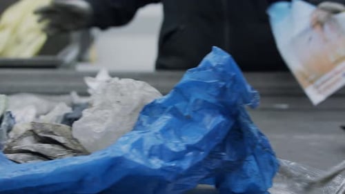 People Sorting Plastic Waste in a Recycling Plant. Worker Picks Up Old Plastic Bags.