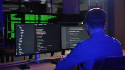 Programmer Working On Computer In IT Office Sitting At Desk Writing Codes