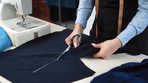 Woman Cuts Dark Blue Fabric at Sewing Table