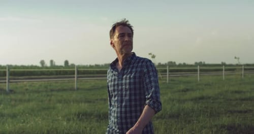 Slow Motion Medium Shot of a Male Farmer Walking Out on the Field of Green Grass. Man