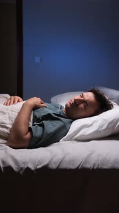 Man laying in bed looking up in darkness