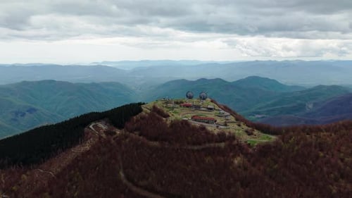 Abandoned radar station on remote mountain peak seen from above in moody cloudy weather