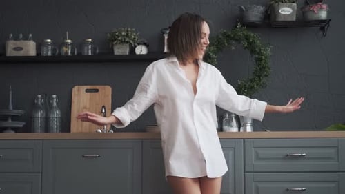 Woman Dances in Kitchen Wearing White Shirt