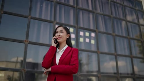 Businesswoman talking to clients and colleague on the phone and working on laptop outside the office