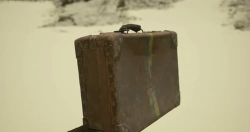 Old Retro Suitcase Rotating on Sand for Travel Concepts