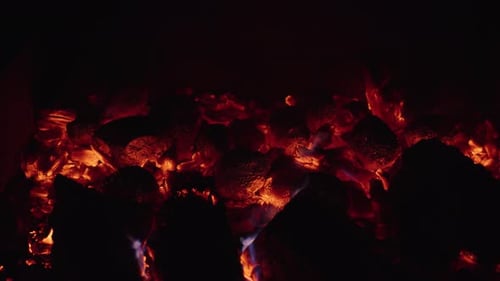 Embers glow in the hearth as flames dance in the cozy fireplace