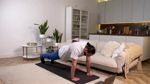 Hombre teniendo un programa de entrenamiento diario viendo Vídeo tutorial en casa