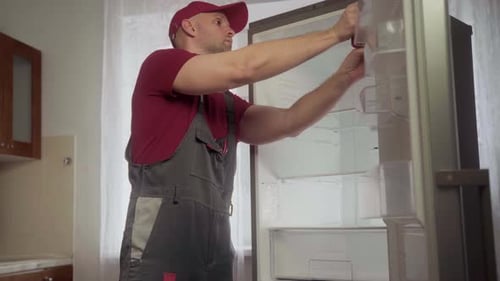 Man Repairing Refrigerator in Kitchen