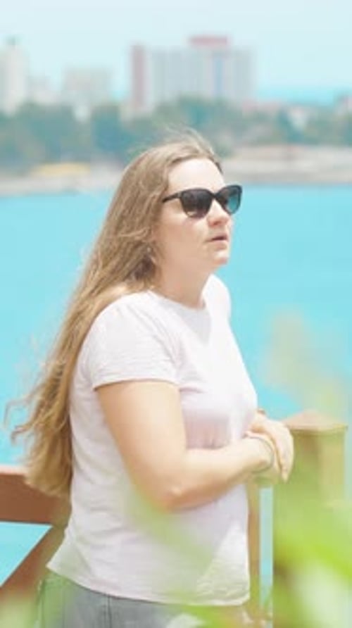 A young woman against the background of blue sea water shows her hand to be approached Vertical. Soc