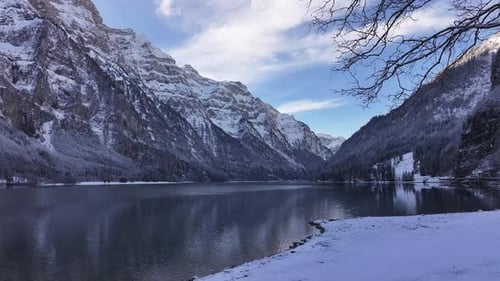 Snowy alpine lake surrounded by majestic peaks on a calm winter day