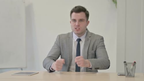 Angry Man Talking at a Desk in Office