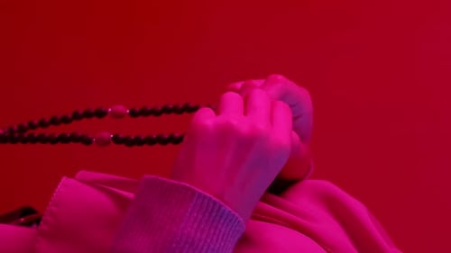 Hands with Prayer Beads in Red Light