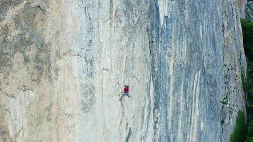 Lone Climber Ascending Steep Rock Face in Wilderness