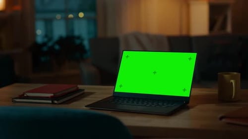 Laptop Computer Showing Green Chroma Key Screen Stands on a Desk in the Living Room. In the Backgro