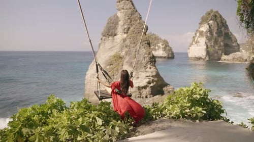 4K video Young woman red dress Play on the swings at Diamond beach
