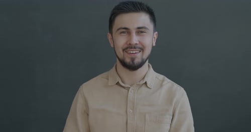 Smiling Man Waving Hello Against Gray Background