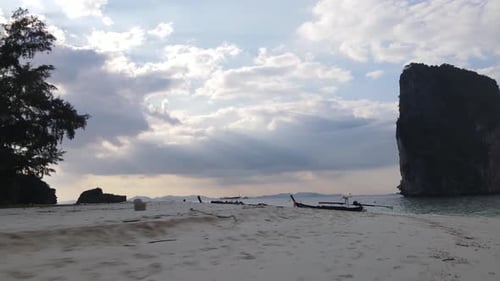 Traditional thai boats moored at a sandy beach between high rocks at the touristic attraction in the