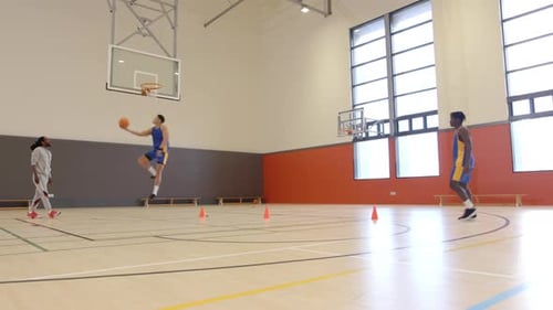 Playing basketball, athletes practicing shooting and passing drills in indoor gym