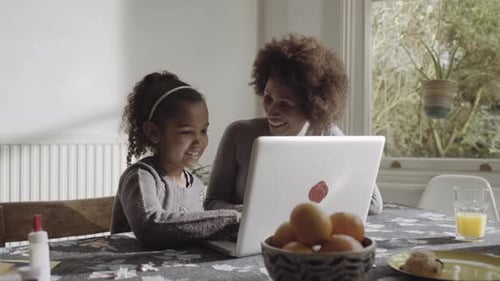 Smiling Mother and Daughter Using Laptop Together