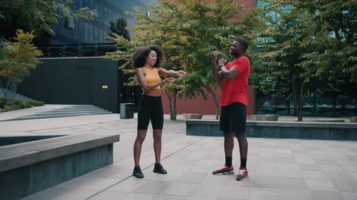 Friendly Couple Stretching Side By Side on Empty Street