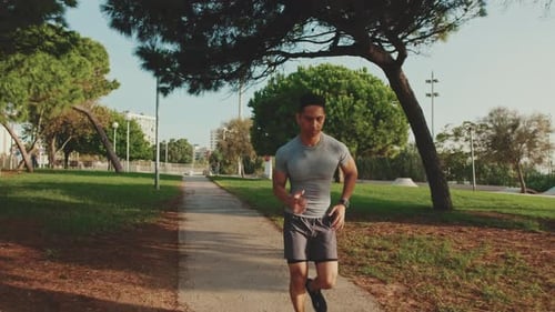 Young man running along the path in the park
