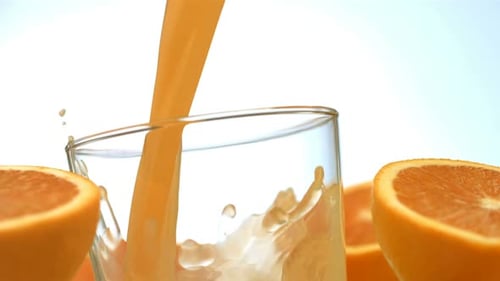 Orange juice being poured into a clear glass