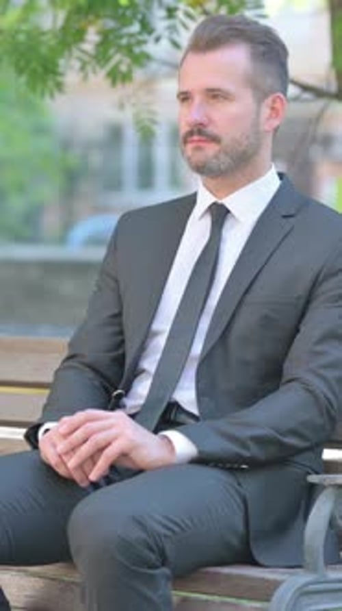 Man in Suit Sitting on Park Bench
