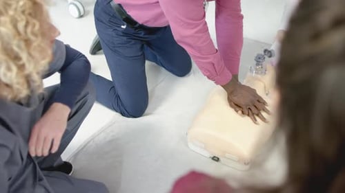 African american doctor training trainee doctors in emergency cpr procedure using dummy, slow motion