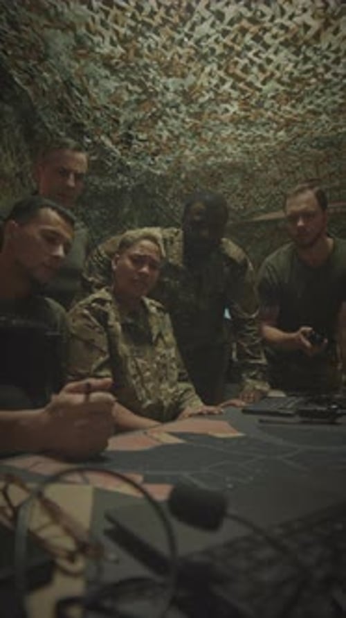 Team Reviews Map in Dark Camouflage Tent