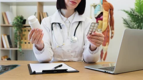 Doctor Holding Medication Bottles and Pills in Medical Office