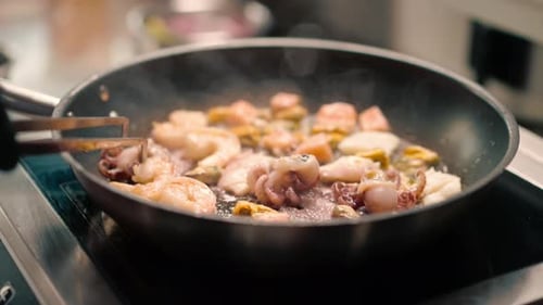 Professional kitchen in the hotel restaurant close-up seafood fried on a pan shrimp squid mussels