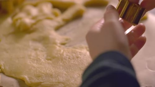 Close up, child's hands pressing cookie cutter shape into raw dough