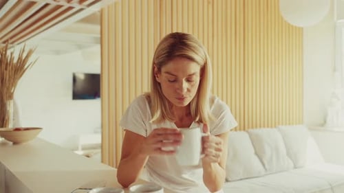 Woman Holding Head Feeling Unwell in Bright Living Room
