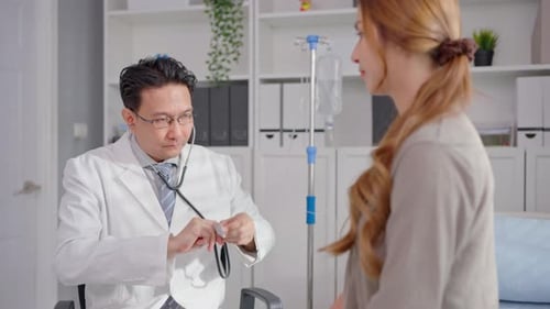 Asian cardiologist doctor listen to heartbeat patient woman in hospital.