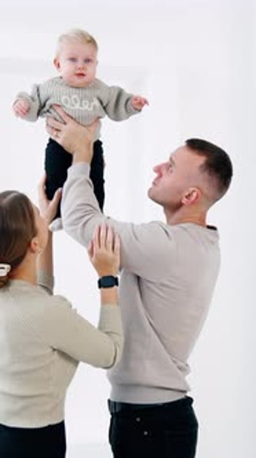 Parents Holding Baby Up in the Air Indoors