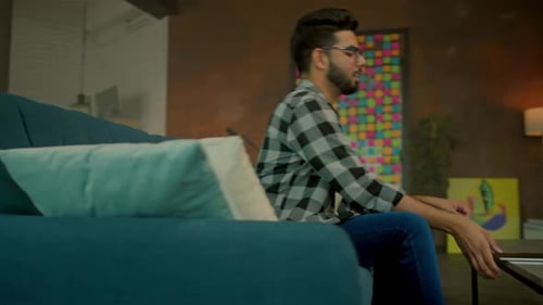 Man Uses Tablet on Couch at Home