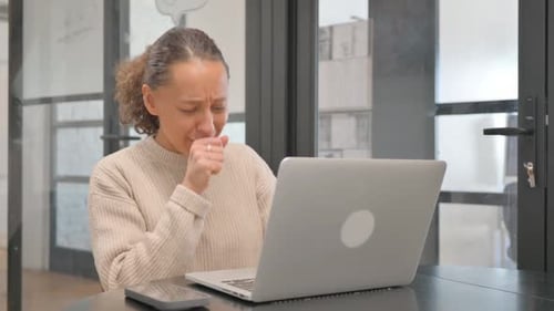Woman Coughs at Desk While Using Laptop