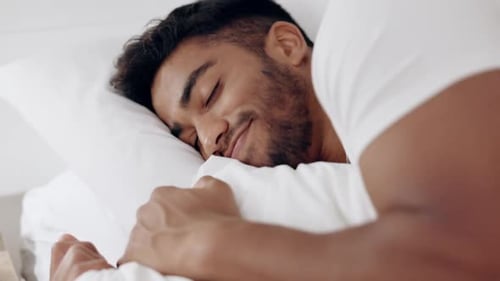 Face of happy man sleeping in bed, morning and at home for relaxing wellness