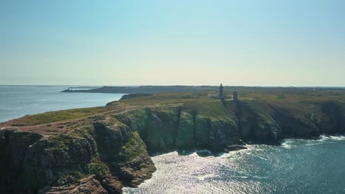 Drohnen-Enthüllung des Leuchtturms und der Klippen von Cap Frehel, rückwärtiger Luftflug über den glitzernden Atlantik