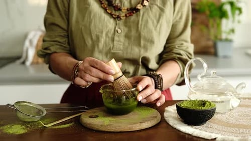 Woman Preparing Matcha Tea with Bamboo Whisk