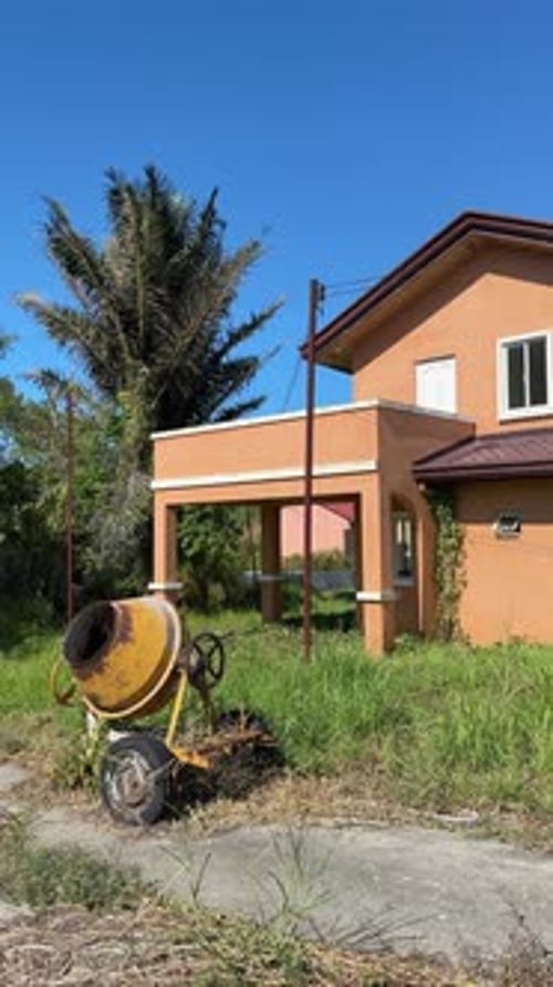 Ground level view of an empty house with peeling paint and visible cracks across exterior walls.