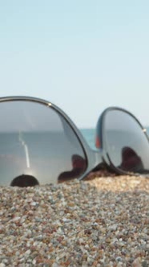 Dinge am Strand am Meer. Durch pinke Flip-Flops und Sonnenbrille und einen roten Apfel. Dolly Vertic